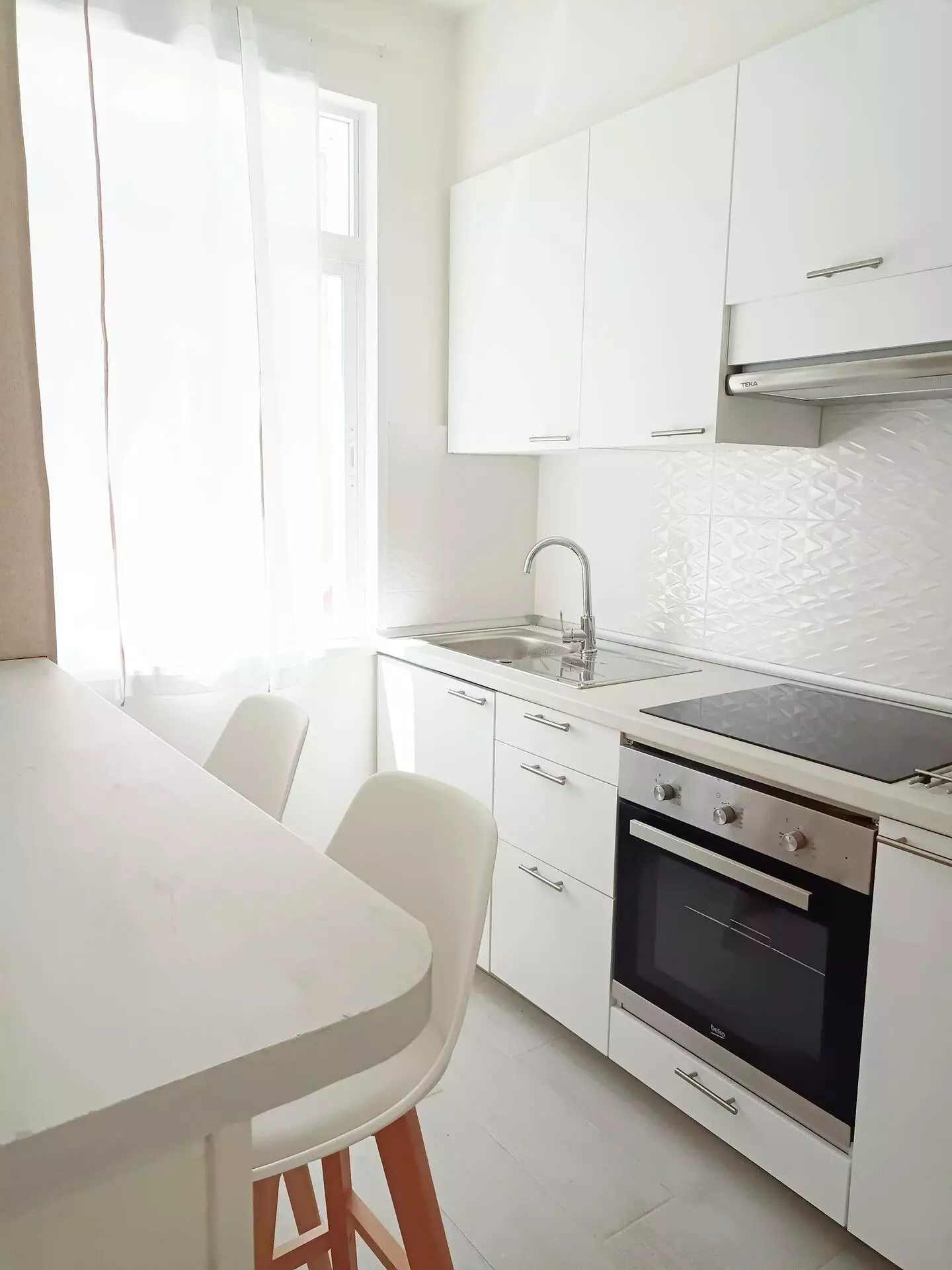 Detalle de la cocina del apartamento, muy luminosa, con barra y taburetes