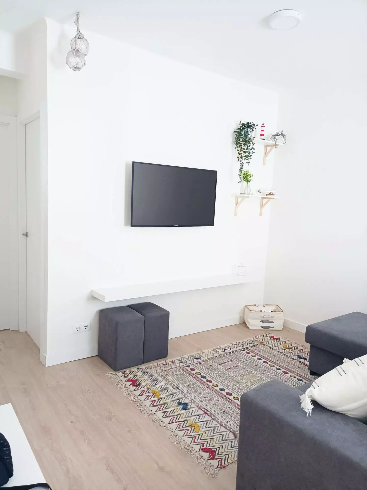 Salón del piso de vacaciones en Cedeira, con televisor, alfombra, estanterías y sofás recién reformados