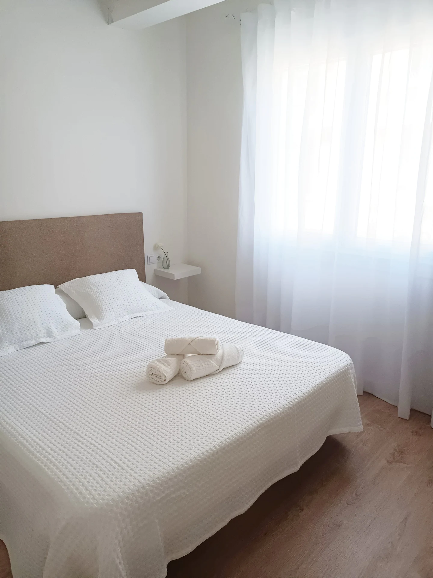 Ventana y cama del dormitorio de matrimonio, apartamento de alquiler para parejas en Cedeira